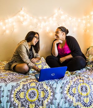 May De Luna and Andrea Gamboa on a bed talking