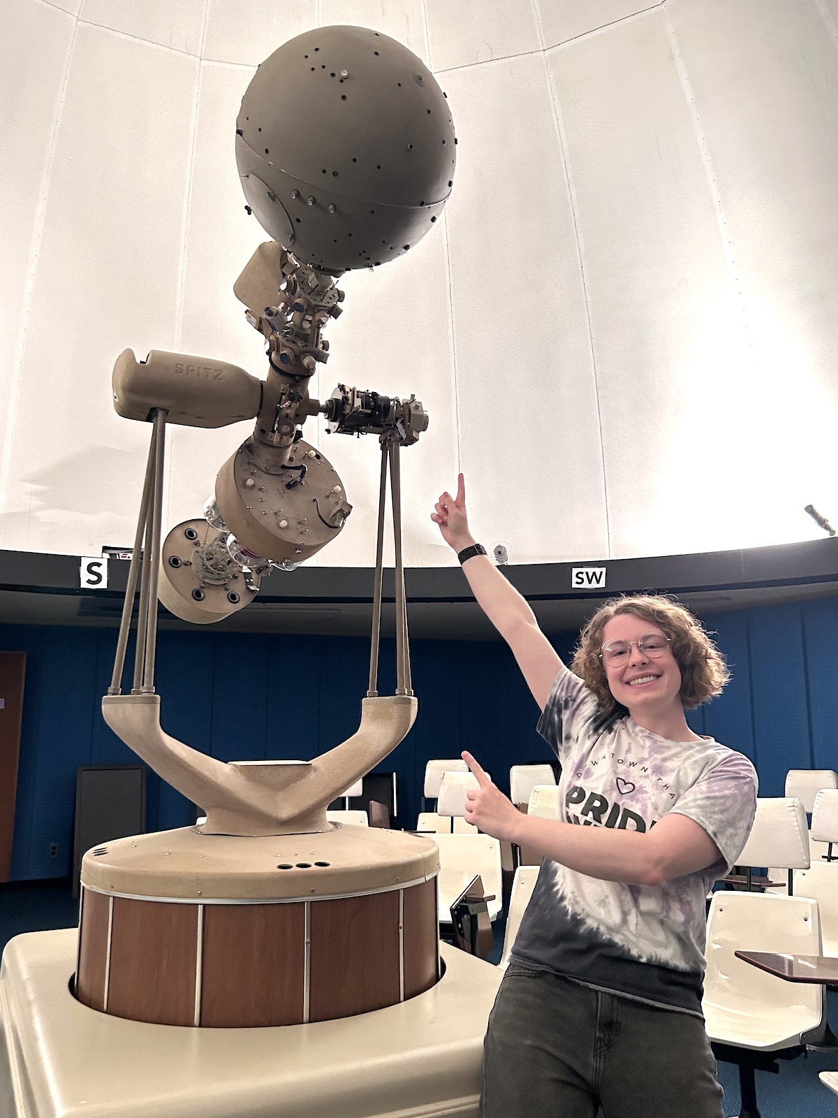 Gillis Lowry standing next to the SFSU Charles Hager Planetarium's old projector