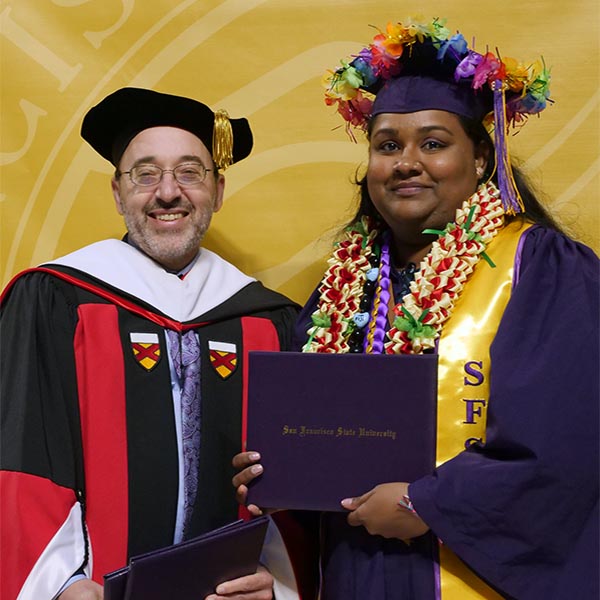 Student graduate posing with professor at commencement