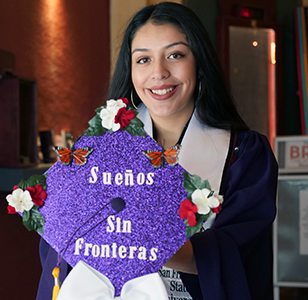 Latina Graduate holding a Suenos Sin Frontieras sign