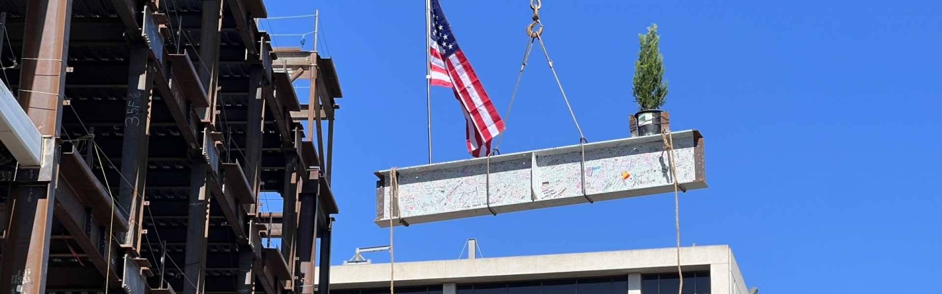 last beam being lifted by crane onto building