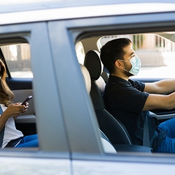 man driving a car with woman in the backseat