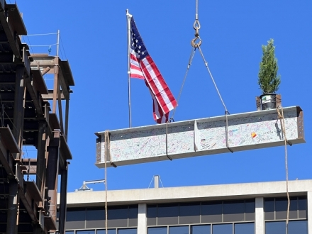 last beam being lifted by crane onto building
